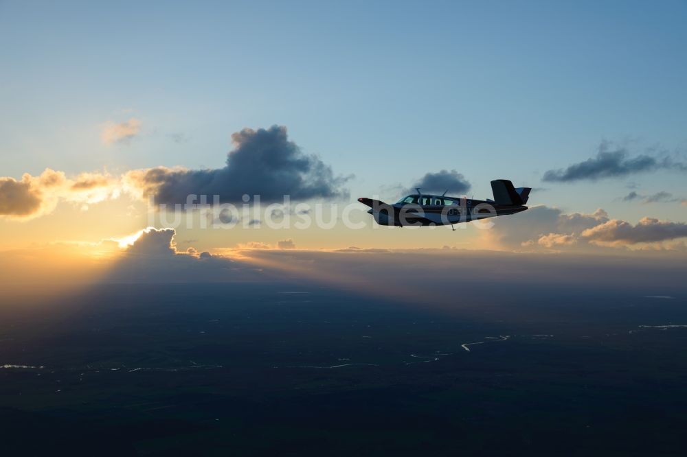 Luftaufnahme Geestland - Beechcraft Bonanza D-EHVC im Fluge im Sonnenuntergang bei Geestland im Bundesland Bremen, Deutschland