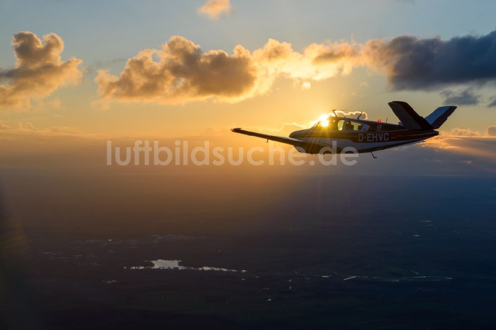 Geestland aus der Vogelperspektive: Beechcraft Bonanza D-EHVC im Fluge im Sonnenuntergang bei Geestland im Bundesland Bremen, Deutschland