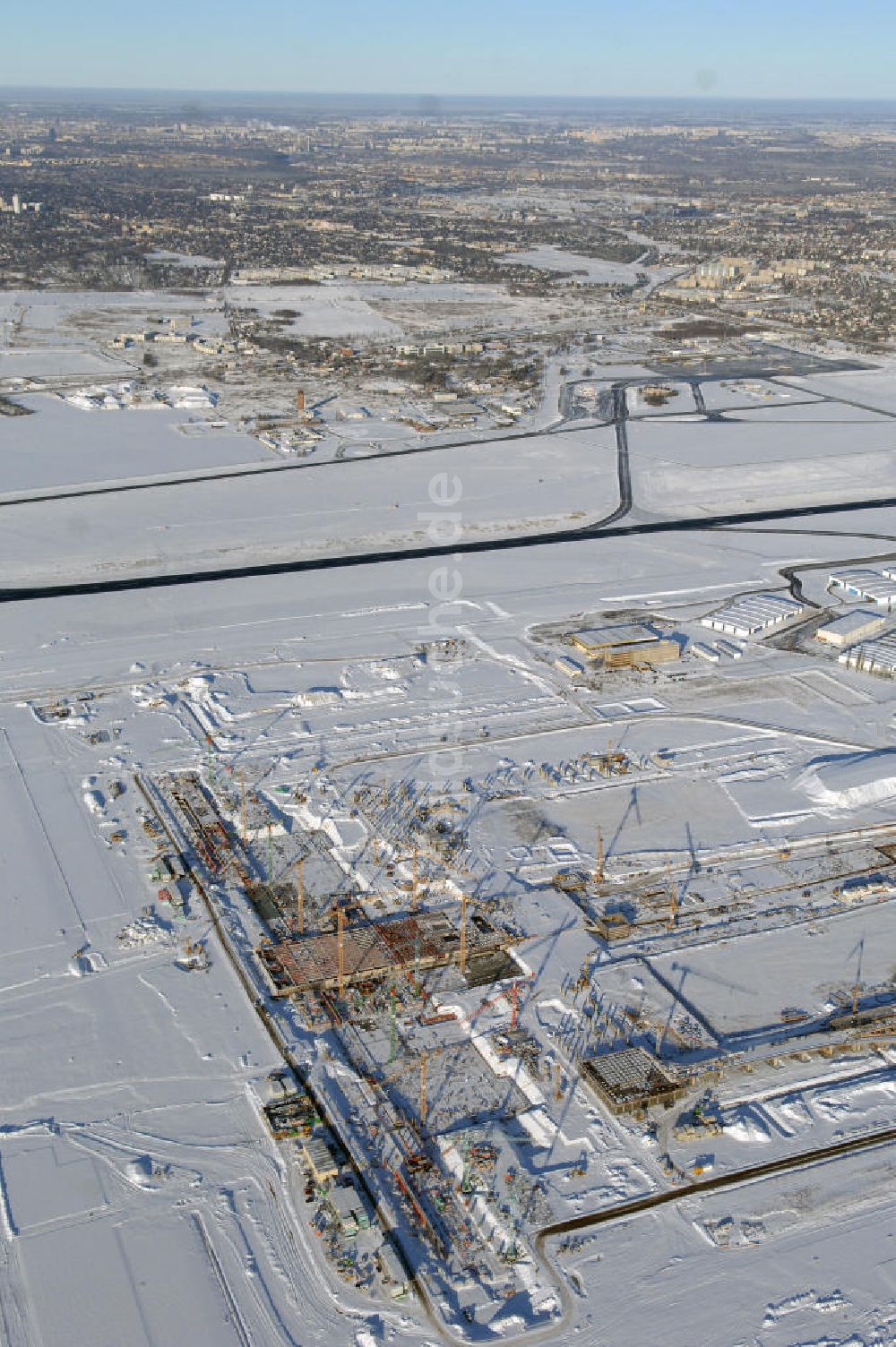 Luftaufnahme SCHÖNEFELD - Blick auf die winterlich verschneite Großbaustelle Neubau Bahnhof BBI am Flughafen Berlin-Schönefeld.