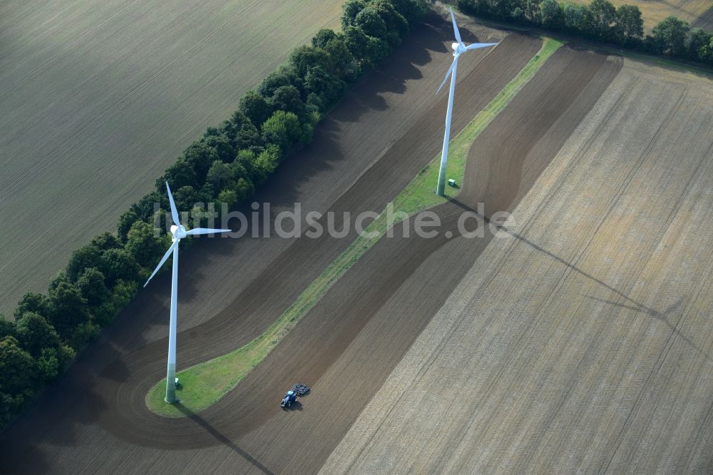 Luftaufnahme Kritzow - Ernte- Traktor umfährt Windenergieanlagen (WEA) - Windrad und Strukturen auf einem Feld in Kritzow im Bundesland Mecklenburg-Vorpommern