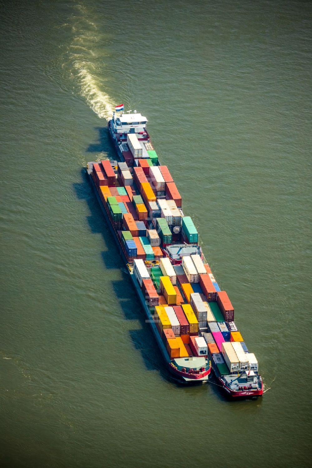 Voerde (Niederrhein) von oben - Fahrendes Containerschiff auf dem Flußverlauf des Rhein in Voerde (Niederrhein) im Bundesland Nordrhein-Westfalen, Deutschland