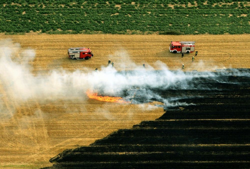 Luftbild Volkenroda - Löscharbeiten der Feuerwehr auf einem kontrollierten Feld - Brand auf einem landwirtschaftlichen Gut bei Volkenroda in Thüringen