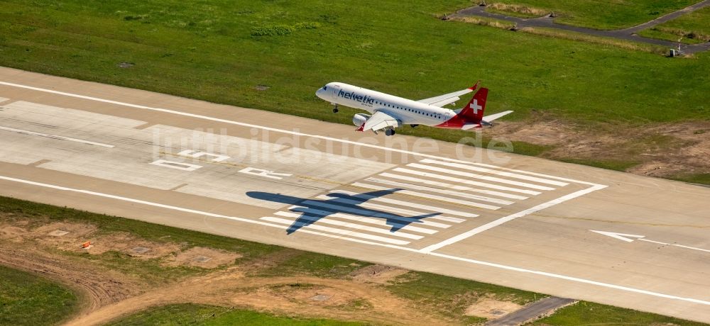 Luftaufnahme Düsseldorf - Passagierflugzeug der helvetic airways über der Start- und Landebahn des Flughafens in Düsseldorf im Bundesland Nordrhein-Westfalen