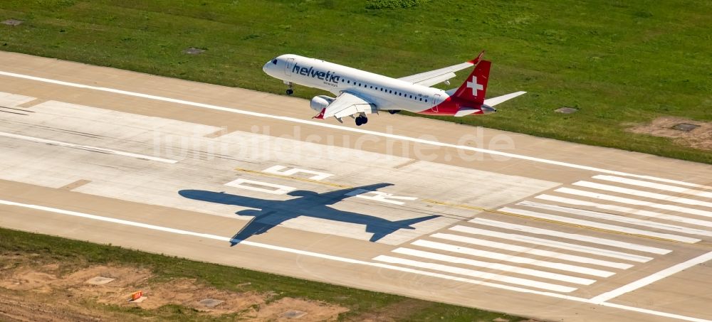 Düsseldorf aus der Vogelperspektive: Passagierflugzeug der helvetic airways über der Start- und Landebahn des Flughafens in Düsseldorf im Bundesland Nordrhein-Westfalen