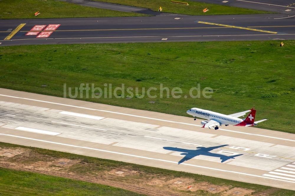 Luftbild Düsseldorf - Passagierflugzeug der helvetic airways über der Start- und Landebahn des Flughafens in Düsseldorf im Bundesland Nordrhein-Westfalen