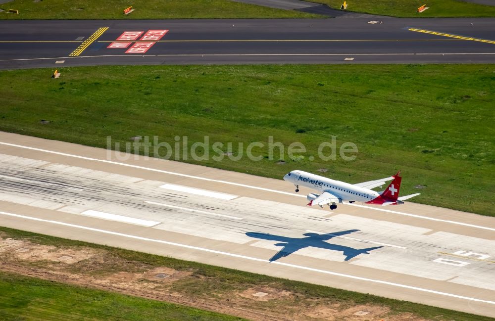 Luftaufnahme Düsseldorf - Passagierflugzeug der helvetic airways über der Start- und Landebahn des Flughafens in Düsseldorf im Bundesland Nordrhein-Westfalen