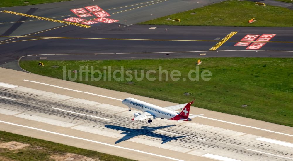 Düsseldorf aus der Vogelperspektive: Passagierflugzeug der helvetic airways über der Start- und Landebahn des Flughafens in Düsseldorf im Bundesland Nordrhein-Westfalen