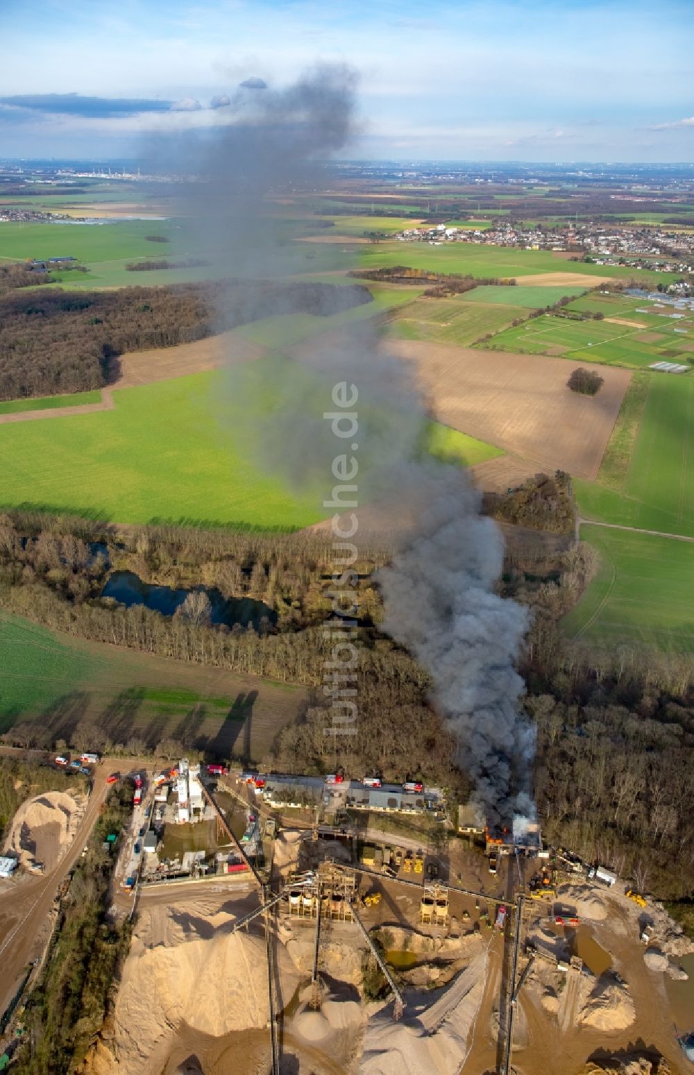 Pulheim aus der Vogelperspektive: Rauch- und Flammenbildung während der Löscharbeiten zum Brand einer Lagerhalle des Terra Kieswerkes am Ufer des Pullheimer See in Pulheim im Bundesland Nordrhein-Westfalen