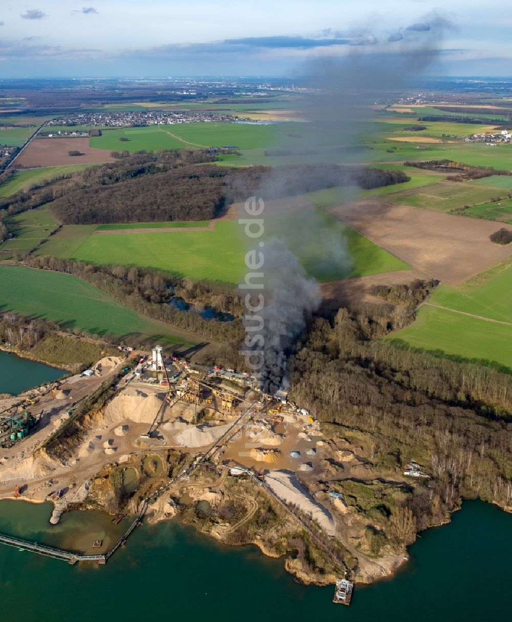 Luftaufnahme Pulheim - Rauch- und Flammenbildung während der Löscharbeiten zum Brand einer Lagerhalle des Terra Kieswerkes am Ufer des Pullheimer See in Pulheim im Bundesland Nordrhein-Westfalen