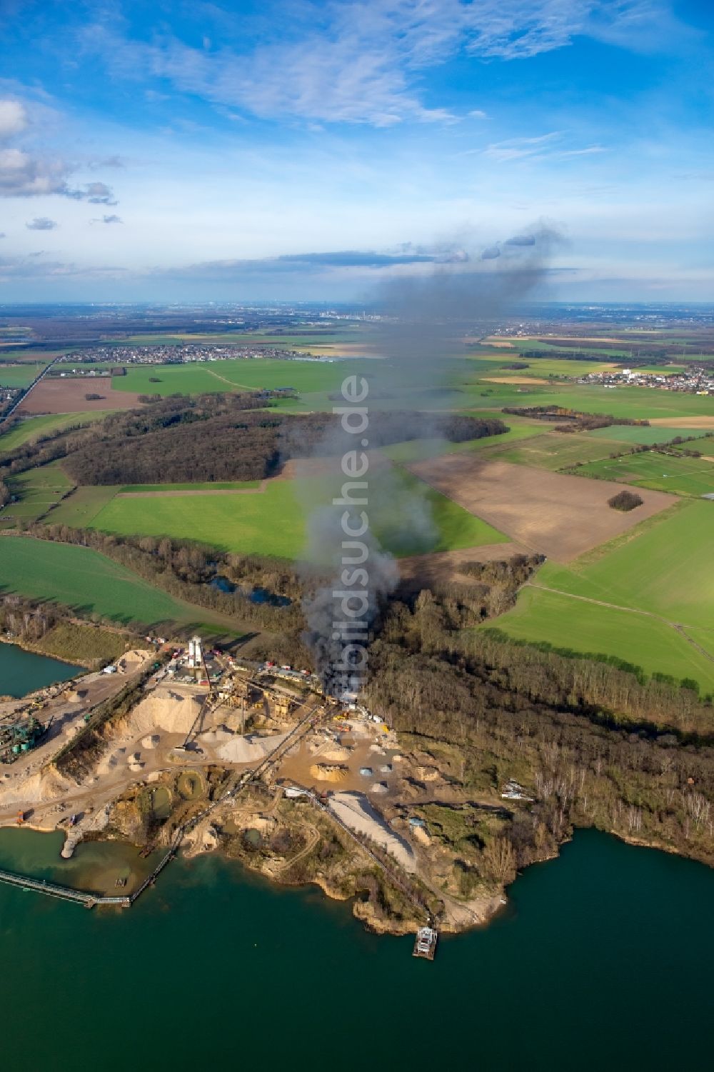 Pulheim von oben - Rauch- und Flammenbildung während der Löscharbeiten zum Brand einer Lagerhalle des Terra Kieswerkes am Ufer des Pullheimer See in Pulheim im Bundesland Nordrhein-Westfalen