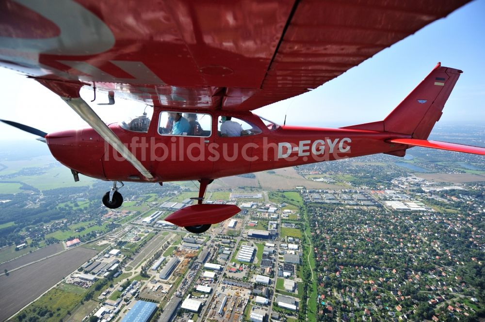 Hoppegarten aus der Vogelperspektive: Rotes Flugzeug Cessna F172H mit der Kennung D-EGYC im Fluge über dem Luftraum im Ortsteil Dahlwitz-Hoppegarten in Hoppegarten im Bundesland Brandenburg, Deutschland