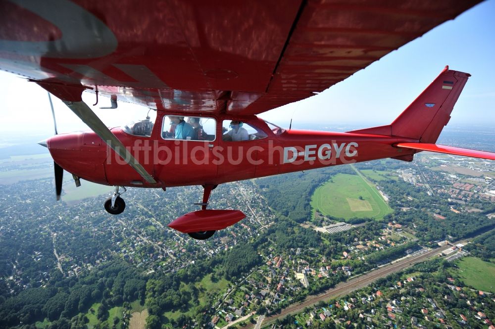 Hoppegarten aus der Vogelperspektive: Rotes Flugzeug Cessna F172H mit der Kennung D-EGYC im Fluge über dem Luftraum im Ortsteil Dahlwitz-Hoppegarten in Hoppegarten im Bundesland Brandenburg, Deutschland