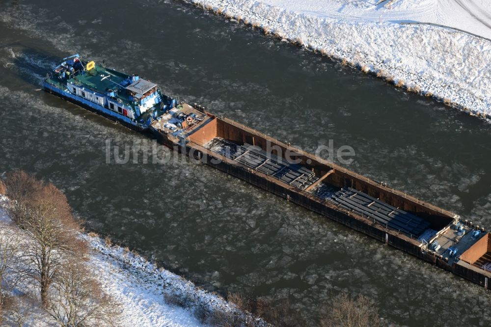 Parey aus der Vogelperspektive: Schiff und Schubverband der Binnenschiffahrt in Fahrt auf der winterlich mit Schnee und Eis bedeckten Flußverlaufes des Elbe-Havel-Kanal in Parey im Bundesland Sachsen-Anhalt