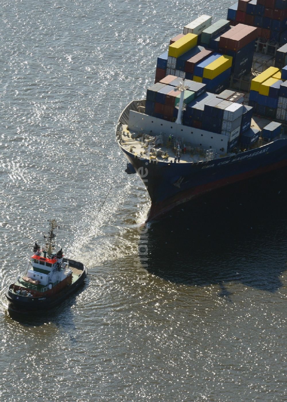 Hamburg von oben - Schlepper vor dem Containerschiff - Frachter CMA CGM MAUPASSANT einer britischen Reederei bei der Fahrt in den Hafenbereich auf dem Elbstrom in Hamburg