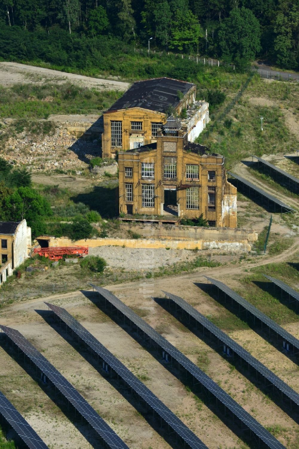 Muldenstein aus der Vogelperspektive: Solarfelder mit Photovoltaikanlagen am Solarkraftwerk an der Fassaden- Ruine des alten Rohrwerkes Muldenstein im Bundesland Sachsen-Anhalt