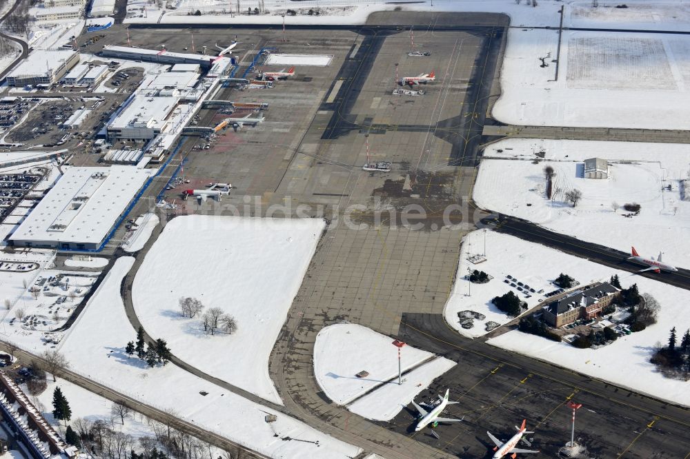 Schönefeld aus der Vogelperspektive: Winterlich mit Schnee bedecktes Rollfeld , Rollwege , Abfertigungshalle und altes DDR- Terminal aus INTERFLUG Zeiten am Flughafen Berlin - Schönefeld