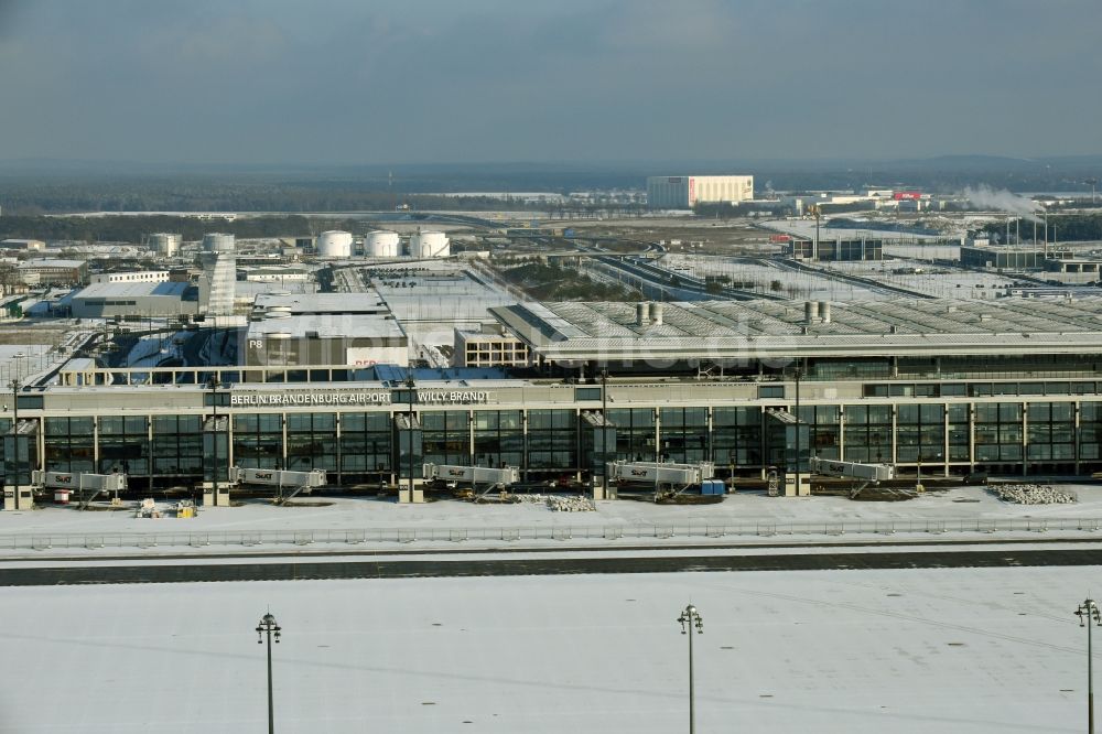 Luftaufnahme Schönefeld - Winterlich schneebedeckte Abfertigungs- Gebäude und Terminals auf dem Gelände des Flughafen in Schönefeld im Bundesland Brandenburg