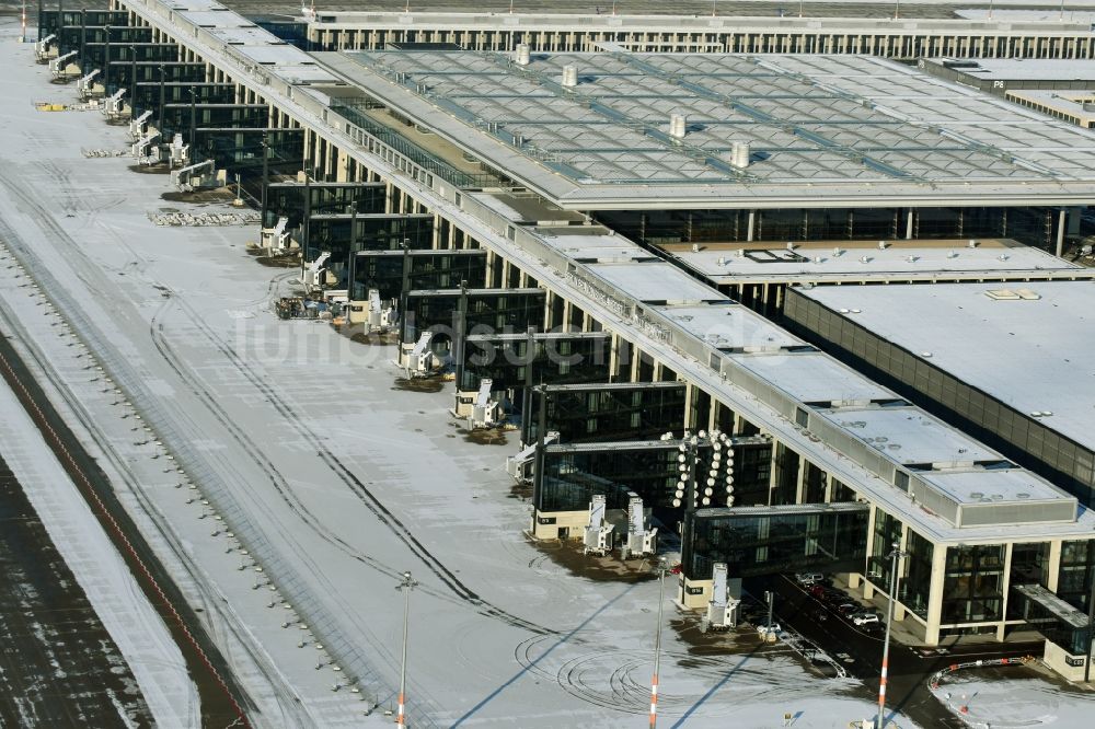 Schönefeld aus der Vogelperspektive: Winterlich schneebedeckte Abfertigungs- Gebäude und Terminals auf dem Gelände des Flughafen in Schönefeld im Bundesland Brandenburg