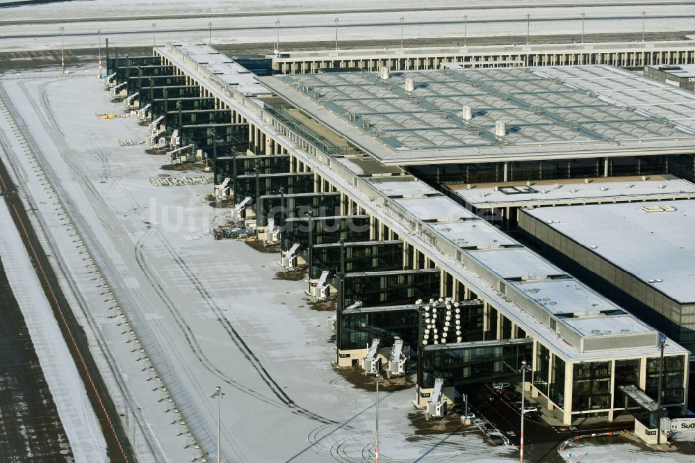 Luftbild Schönefeld - Winterlich schneebedeckte Abfertigungs- Gebäude und Terminals auf dem Gelände des Flughafen in Schönefeld im Bundesland Brandenburg