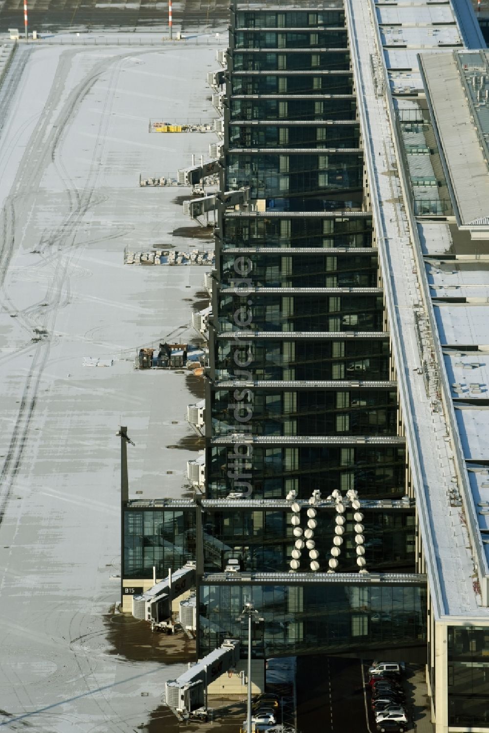 Luftaufnahme Schönefeld - Winterlich schneebedeckte Abfertigungs- Gebäude und Terminals auf dem Gelände des Flughafen in Schönefeld im Bundesland Brandenburg