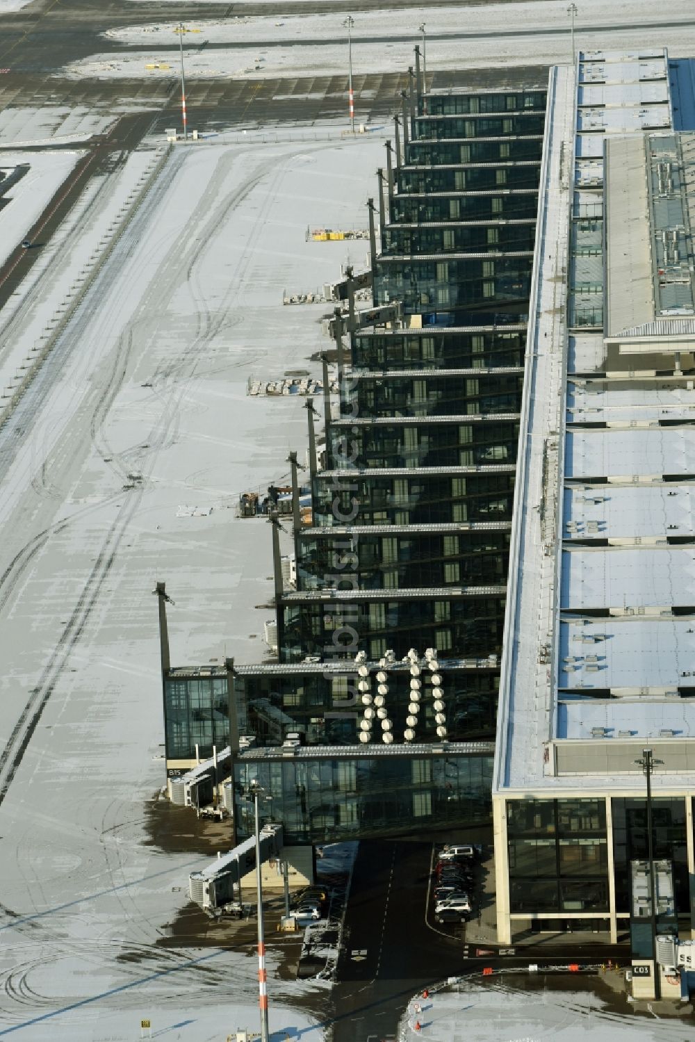 Schönefeld aus der Vogelperspektive: Winterlich schneebedeckte Abfertigungs- Gebäude und Terminals auf dem Gelände des Flughafen in Schönefeld im Bundesland Brandenburg