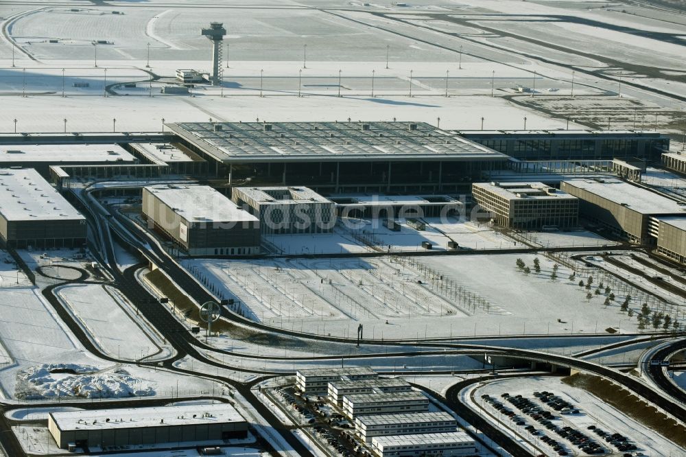 Luftaufnahme Schönefeld - Winterlich schneebedeckte Abfertigungs- Gebäude und Terminals auf dem Gelände des Flughafen in Schönefeld im Bundesland Brandenburg