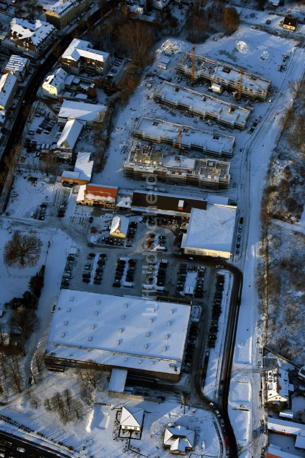 Luftaufnahme Berlin - Winterlich schneebedeckte Baustelle zum Neubau einer Mehrfamilienhaus-Wohnanlage An der Schule im Stadtteil Mahlsdorf in Berlin