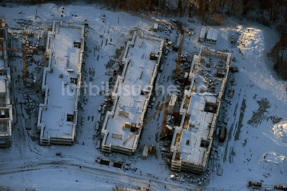 Luftaufnahme Berlin - Winterlich schneebedeckte Baustelle zum Neubau einer Mehrfamilienhaus-Wohnanlage An der Schule im Stadtteil Mahlsdorf in Berlin