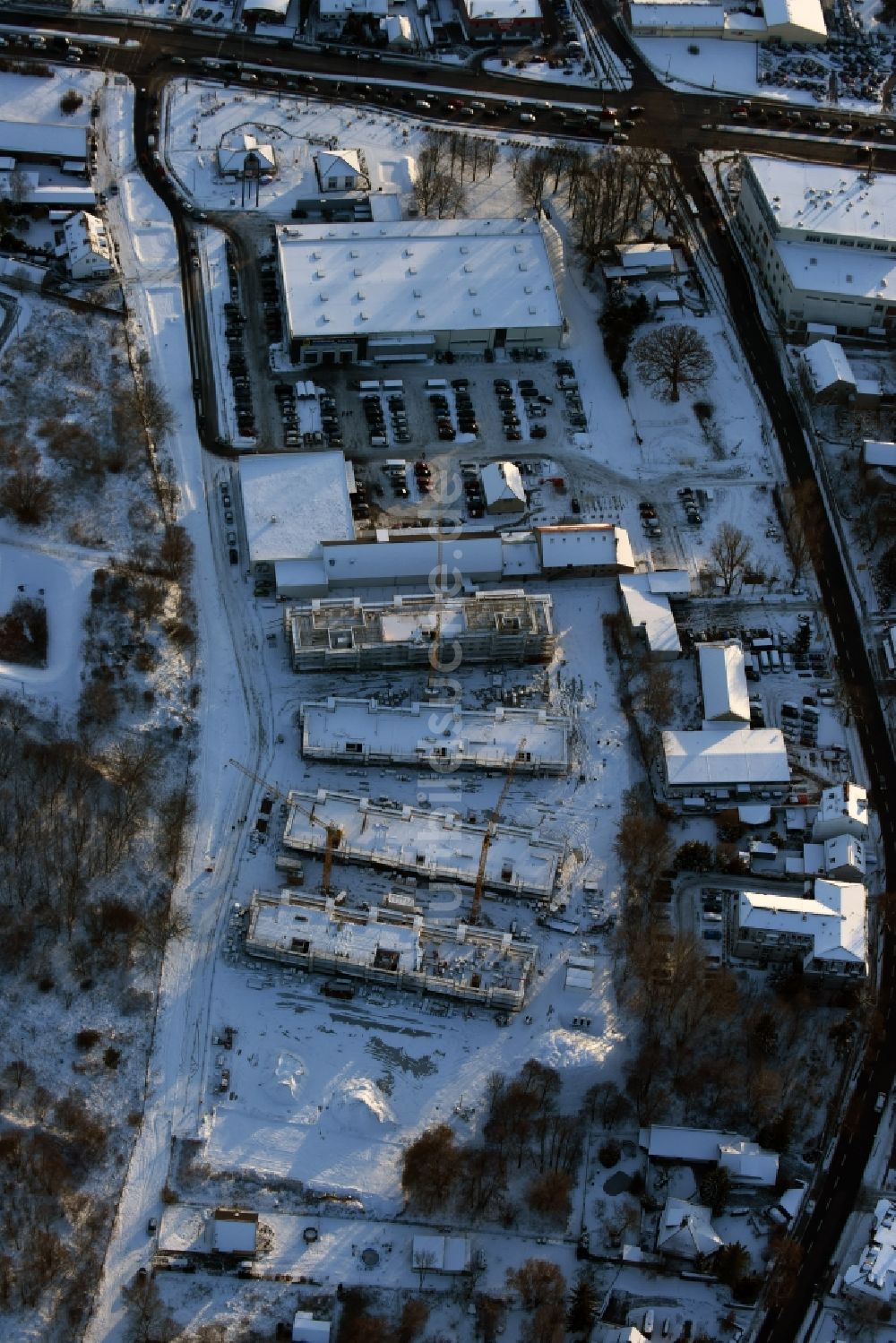 Luftaufnahme Berlin - Winterlich schneebedeckte Baustelle zum Neubau einer Mehrfamilienhaus-Wohnanlage An der Schule im Stadtteil Mahlsdorf in Berlin