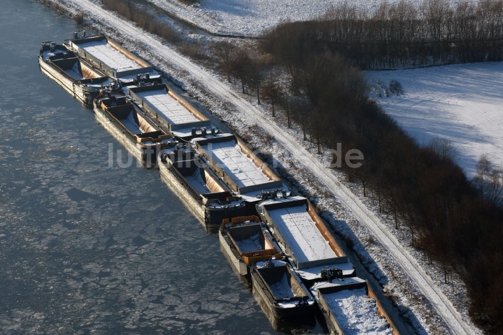 Burg aus der Vogelperspektive: Winterlich schneebedeckter Kanalverlauf mit festgemachten Lastkahn- Binnenschiff- Schubeinheiten am Ufer des Elbe-Havel-Kanal bei Burg im Bundesland Sachsen-Anhalt